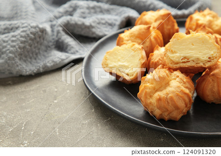 Homemade profiteroles with cream on plate on grey background. Fresh baked golden profiterole. 124091320