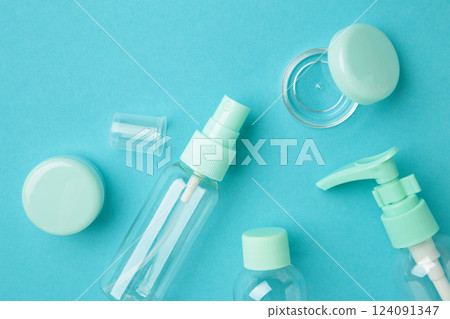 Empty travel cosmetic bottles on blue background. Minimalist bodycare beauty products for vacation or journey. Top view. Copyspace. 124091347