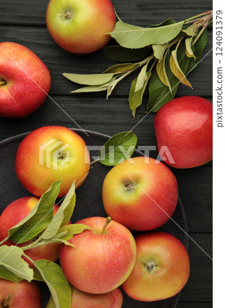 Group of red apples with their leaves on black background. Vertical photo 124091379