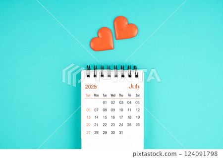 July 2025 desk calendar with red heart on blue background. 124091798