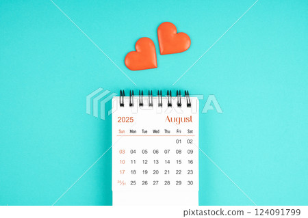August 2025 desk calendar with red heart on blue background. 124091799