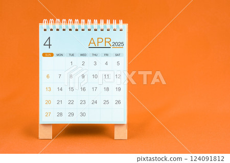 April 2025 desk calendar stand on orange textile background. April 2025 desk calendar stand on orange textile background. 124091812