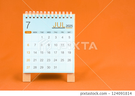 July 2025 desk calendar stand on orange textile background. July 2025 desk calendar stand on orange textile background. 124091814