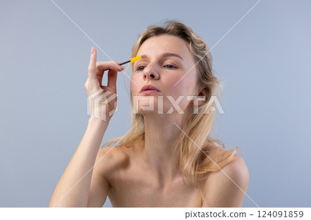 Woman with Long Hair Applying Brow Gel to Shape Her Eyebrows in Natural Light with Soft Background for a Beauty, Skincare, and Makeup Inspiration 124091859