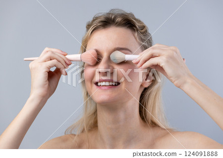 A Cheerful Woman Applying Makeup with Blush Brushes: Embracing Beauty and Creativity 124091888