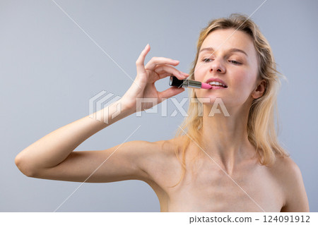 A Beautiful Woman Applying Pink Lipstick as Part of Her Daily Beauty Routine with a Natural and Confident Expression in a Minimalistic Setting A Beautiful Woman Applying Pink Lipstick as Part of Her Daily Beauty Routine with a Natural and Confident Expression in a Minimalistic Setting 124091912