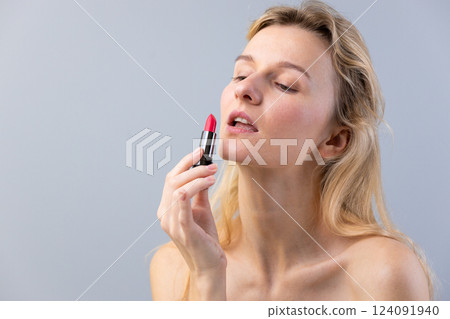 Captivating Close-Up of a Woman Applying Vibrant Red Lipstick, Highlighting Beauty and Confidence in a Minimalist Composition with Soft Lighting Captivating Close-Up of a Woman Applying Vibrant Red Lipstick, Highlighting Beauty and Confidence in a Minimalist Composition with Soft Lighting 124091940