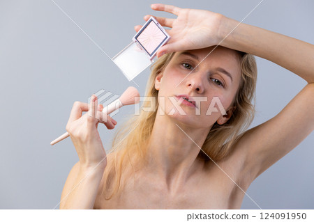 A Close-Up of a Young Woman Applying Makeup with a Subtle Expression and Elegant Technique in a Simple Studio Setting with Soft Lighting for a Stylish Beauty Shoot A Close-Up of a Young Woman Applying Makeup with a Subtle Expression and Elegant Technique in a Simple Studio Setting with Soft Lighting for a Stylish Beauty Shoot 124091950