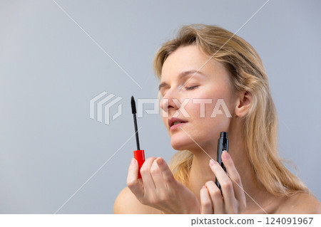 A Woman Applying Mascara to Enhance Her Eyes While Discovering the Beauty of Makeup and Self-Care in a Cozy, Minimalistic Environment 124091967