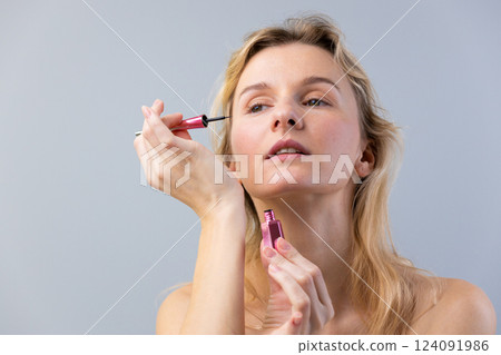 A Beautiful Woman Applying Makeup with Pink Cosmetics in a Minimalist Setting for a Stunning Look That Emphasizes Natural Beauty and Self-Care Rituals A Beautiful Woman Applying Makeup with Pink Cosmetics in a Minimalist Setting for a Stunning Look That Emphasizes Natural Beauty and Self-Care Rituals 124091986