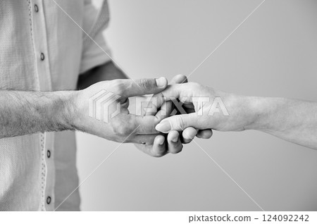 Close up of two hands engaging in delicate touch. Man's and woman's hands on white neutral background. Husband holding hand of his lovely wife. Concept of support, mutual respect. Black and white. 124092242
