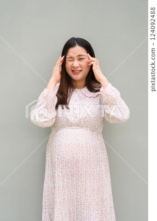 Pregnant woman portrait against plain wall 124092488