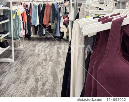 a clothing section inside a retail store, focusing on neatly arranged activewear tank tops in the foreground 124093012