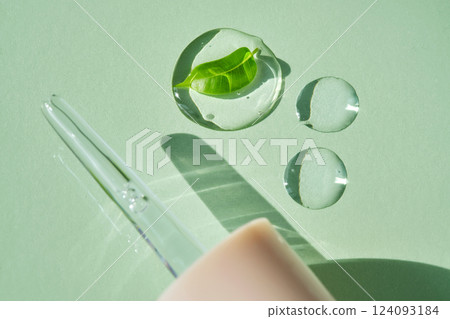 A drops of serum with a leaf and dropper on a green background. A drops of serum with a leaf and dropper on a green background. 124093184