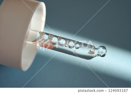 Pipette with serum on blue background with sunlight. 124093187