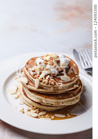 Stack of breakfast pancakes with sour cream, syrup and nuts. Stack of breakfast pancakes with sour cream, syrup and nuts. 124093300