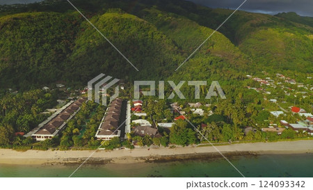 Aerial drone captures a breathtaking view of a tropical resort nestled between lush green mountains and the tranquil ocean, showcasing the beauty of nature and the allure of a luxurious getaway Aerial drone captures a breathtaking view of a tropical resort nestled between lush green mountains and the tranquil ocean, showcasing the beauty of nature and the allure of a luxurious getaway 124093342
