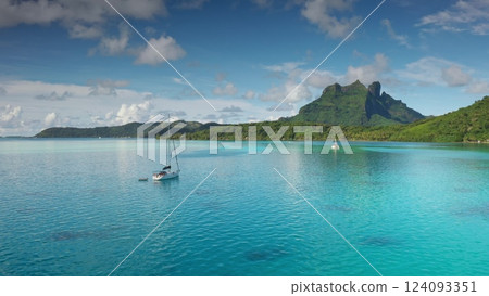 Breathtaking aerial view, two sailboats enjoy crystal clear water of Bora Bora lagoon, green mountain majestically rising in background under a vibrant sky. Perfect wild nature travel background Breathtaking aerial view, two sailboats enjoy crystal clear water of Bora Bora lagoon, green mountain majestically rising in background under a vibrant sky. Perfect wild nature travel background 124093351