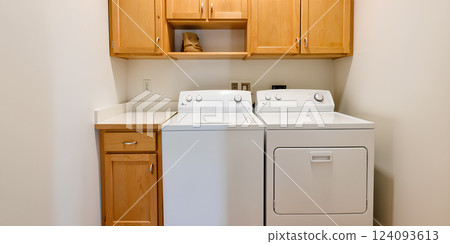 A modern washing machine against a white wall in a laundry room - 3D rendering. A modern washing machine against a white wall in a laundry room - 3D rendering. 124093613