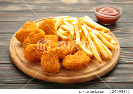 Plate of chicken nuggets with french fries and ketchup on cutting board Plate of chicken nuggets with french fries and ketchup on cutting board 124093802