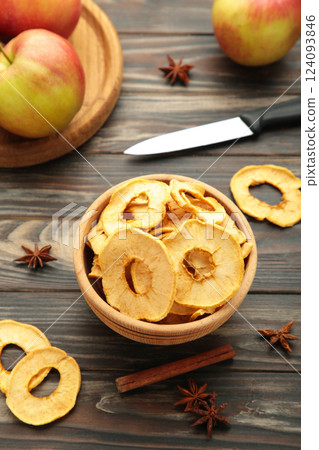 Dried apple chips with cinnamon and star anise with fresh apple. Homemade dried organic apple sliced on brown wooden background. Dried apple chips with cinnamon and star anise with fresh apple. Homemade dried organic apple sliced on brown wooden background. 124093846