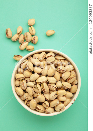 Bowl with pistachios on mint background. Vertical photo 124093887