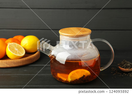 Black tea with lemon in glass teapot on black background. Healthy drink concept. Black tea with lemon in glass teapot on black background. Healthy drink concept. 124093892
