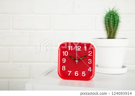 Good morning concept - modern alarm clock and houseplant on bedside table Good morning concept - modern alarm clock and houseplant on bedside table 124093914