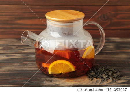 Black tea with lemon in glass teapot on brown background. Healthy drink concept. 124093917