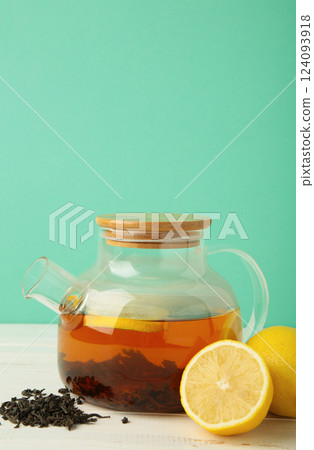 Black tea with lemon in glass teapot on mint background. Healthy drink concept. 124093918