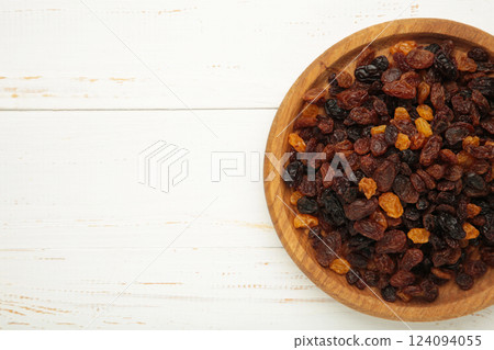 Raisins in wooden bowl on white background. Raisins in wooden bowl on white background. 124094055
