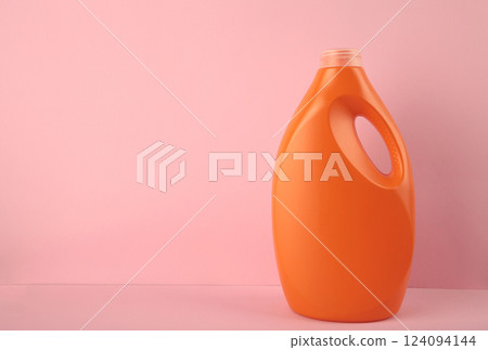 Orange plastic bottle with liquid laundry detergent or cleaning agent or bleach or fabric softener on pink background. Orange plastic bottle with liquid laundry detergent or cleaning agent or bleach or fabric softener on pink background. 124094144