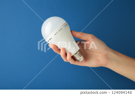 Light bulb in hand on blue background. Space for text Light bulb in hand on blue background. Space for text 124094148