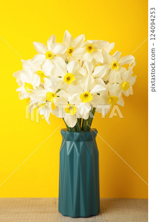 Spring easter background with daffodils bouquet in vase on yellow background. Vertical photo Spring easter background with daffodils bouquet in vase on yellow background. Vertical photo 124094253