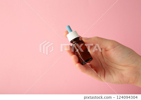 Hand holds a bottle of nasal drops on pink background. Space for text Hand holds a bottle of nasal drops on pink background. Space for text 124094304