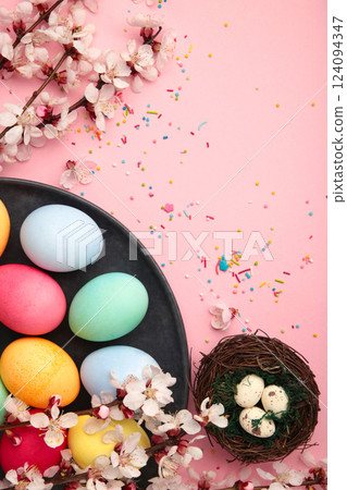 Happy Easter. Colorful Easter chocolate eggs with cherry blossoms on pink background. Greeting card or banner. Vertical photo 124094347