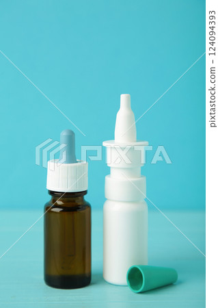 Bottles of nasal drops on blue background. Vertical photo 124094393