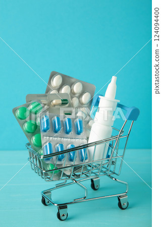 Shopping cart loaded with pills on blue background. The concept of medicine and the sale of drugs. Vertical photo 124094400