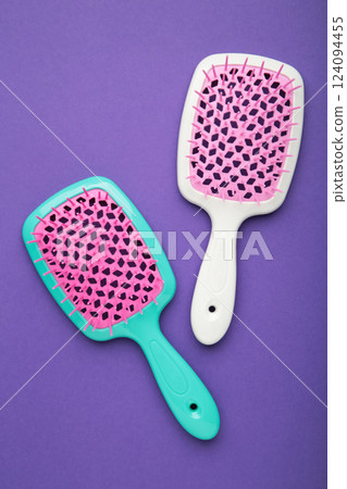 Plastic hairbrushes on violet background. Vertical photo Plastic hairbrushes on violet background. Vertical photo 124094455