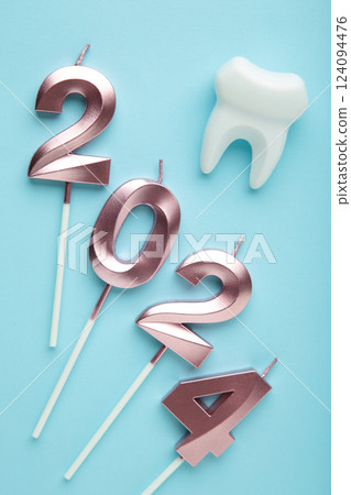 Figure 2024 and tooth with Christmas decoration on blue background. Vertical photo Figure 2024 and tooth with Christmas decoration on blue background. Vertical photo 124094476