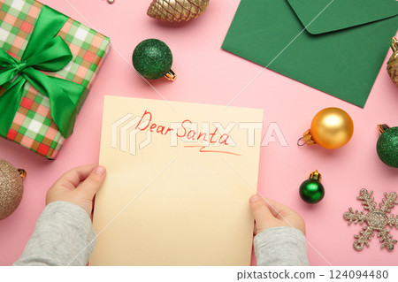 Christmas letter from a child to Santa Claus with the words: Dear Santa. Christmas composition with yellow and green balls on pink background. 124094480
