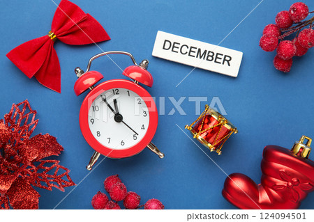 December 2024 Monthly calendar year with alarm clock and Christmas toys on blue background. 124094501