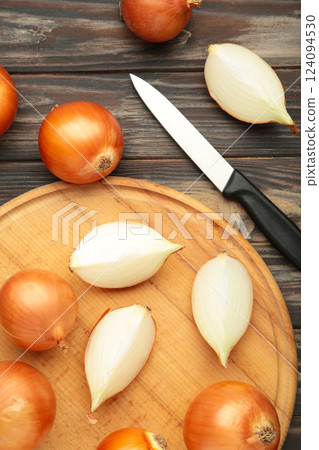 Fresh healthy onions and sliced onion on cutting board on brown background. Vertical photo 124094530