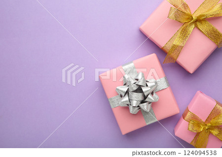 Pink gift boxes with silver and gold bow on purlpe background. 124094538