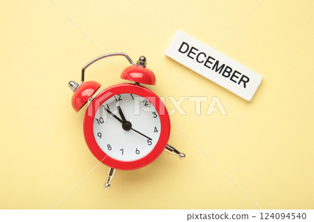 December 2024 Monthly calendar year with alarm clock on beige background. 124094540
