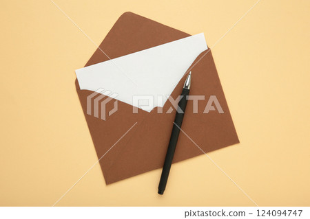 Brown envelope with pen on beige background 124094747