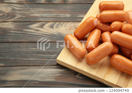 Chicken cocktail sausage on cutting board on brown wooden background. Space for text Chicken cocktail sausage on cutting board on brown wooden background. Space for text 124094749