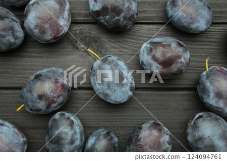 Ripe plums on black wooden background. The autumn harvest. 124094761