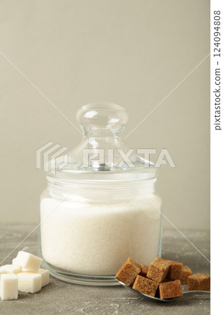 Jar with white sugar on grey background. Space for text. Vertical photo 124094808