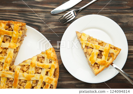 Apple pie and piece of pie on brown background. Copy space. Apple pie and piece of pie on brown background. Copy space. 124094814